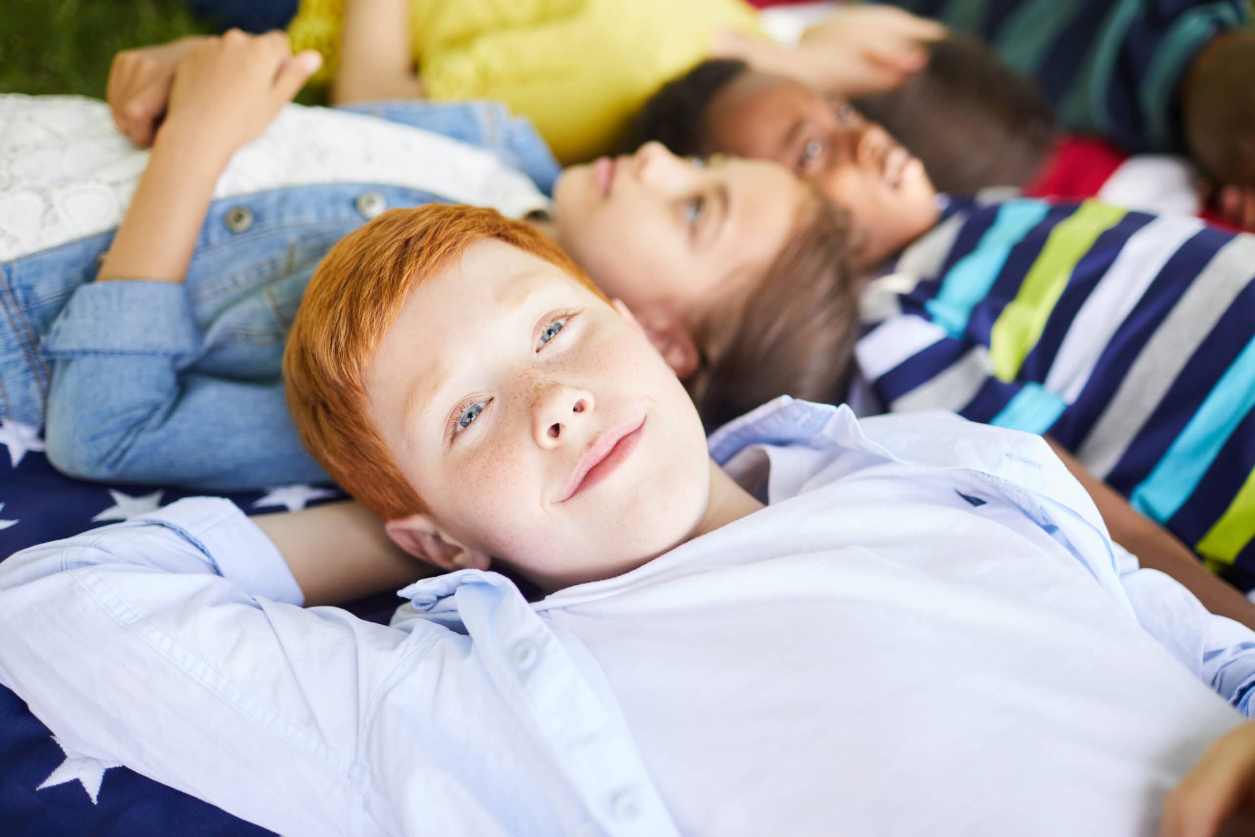 Close-up of a group of children laying on the floor thinking.