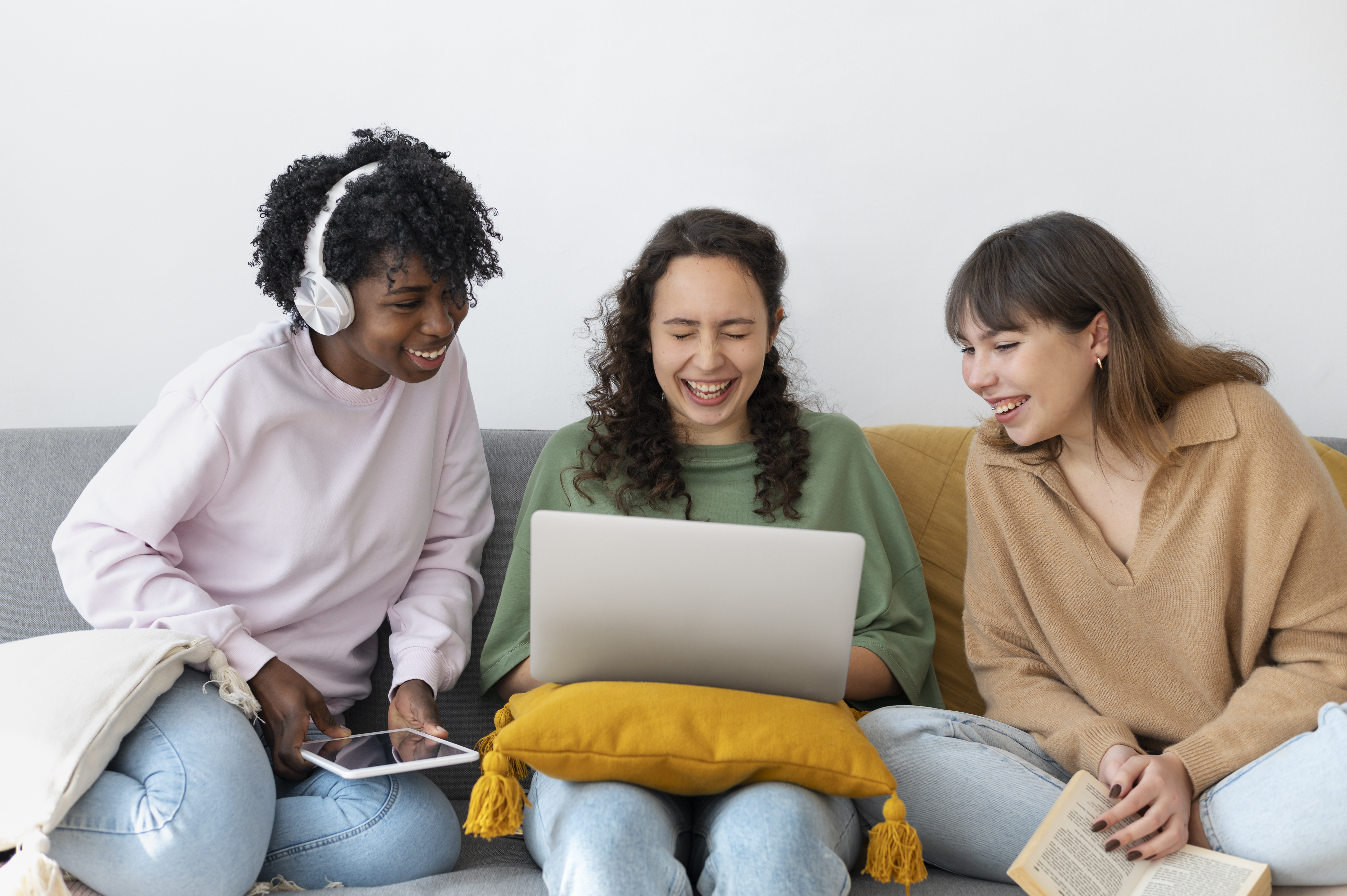 three young people sat looking at one laptop